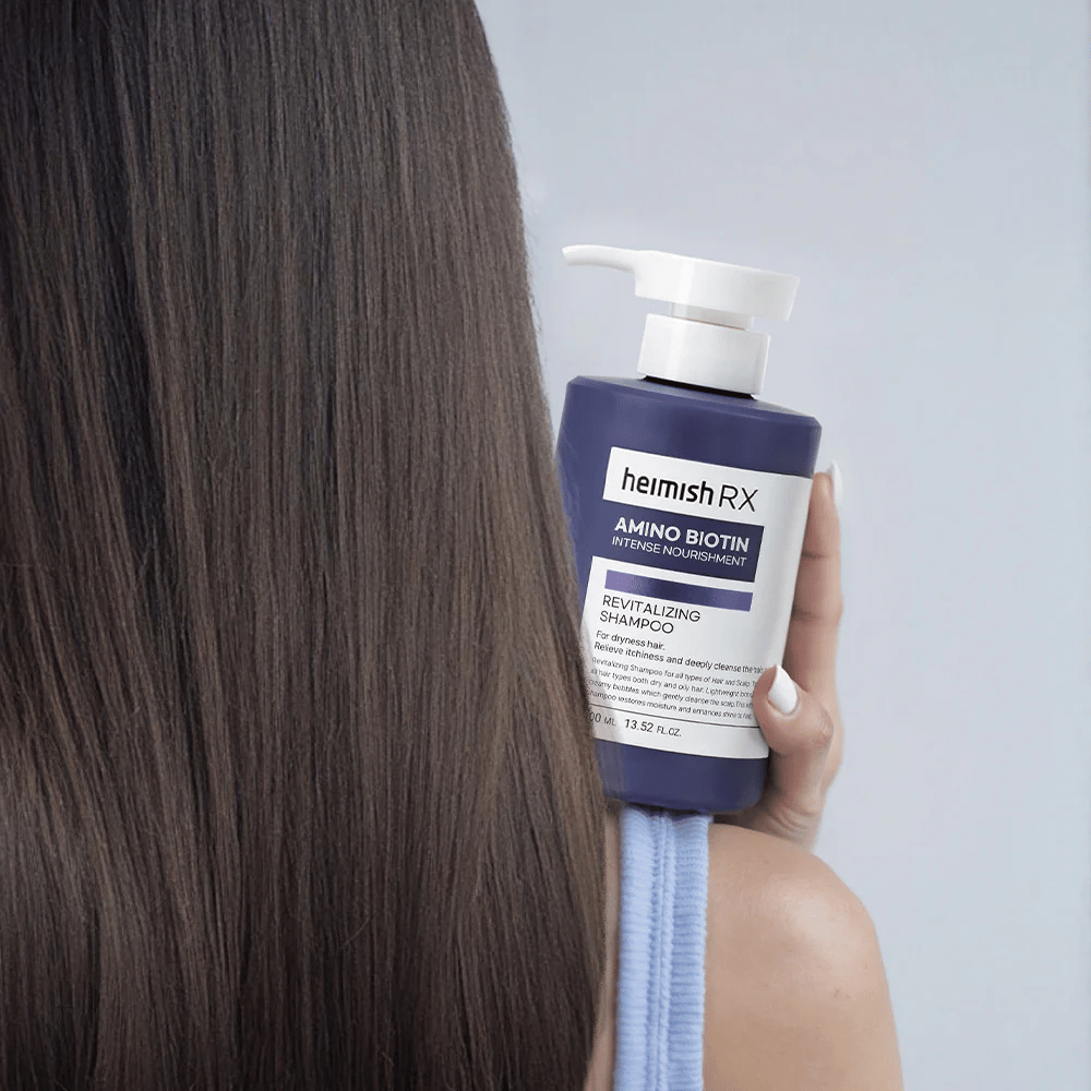 Heimish RX Amino Biotin Revitalizing Shampoo se sostiene en la mano contra el cabello largo y brillante – muestra el resultado de la nutrición intensiva e hidratación para el cabello seco.