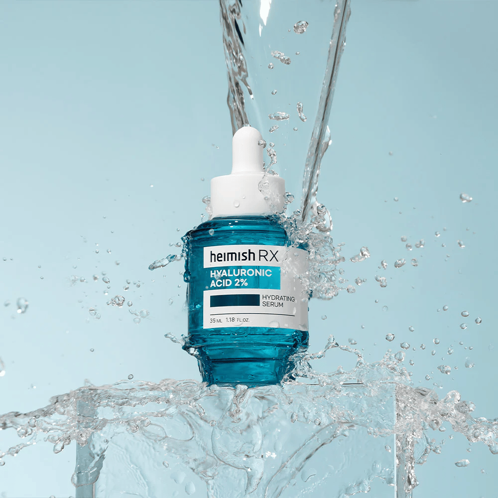 Heimish RX Suero Hidratante de Ácido Hialurónico 2% colocado sobre una superficie similar al hielo con agua salpicando alrededor, simbolizando hidratación intensa y frescura.