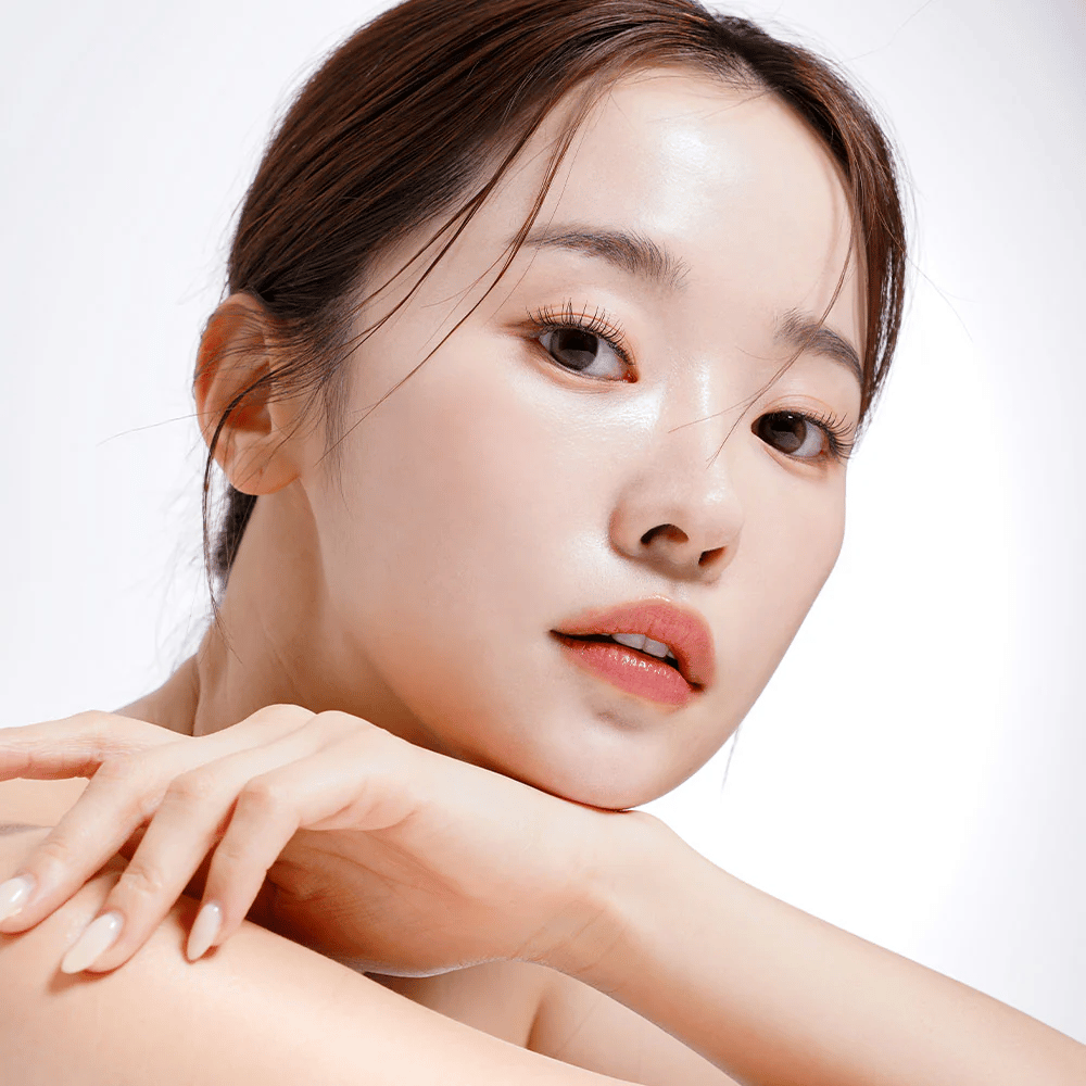 Primer plano de una mujer con piel radiante e hidratada. Su belleza natural se destaca con una iluminación suave, lo que le da un aspecto fresco y saludable.