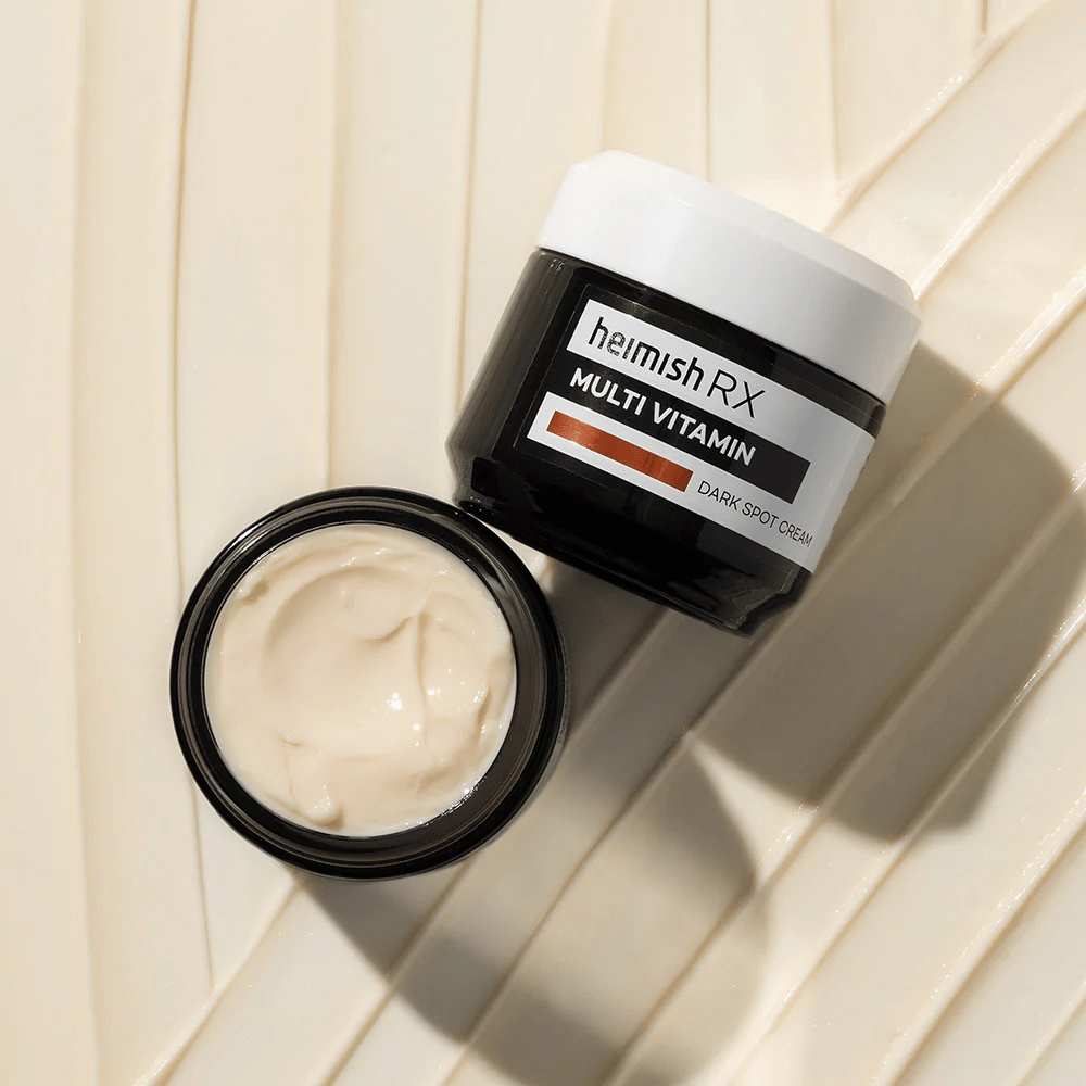 heimish RX Multi Vitamin Dark Spot Cream – una crema facial nutritiva para reducir manchas oscuras y dar a la piel un tono más uniforme. La textura suave de la crema se muestra en un frasco abierto con un empaque elegante.