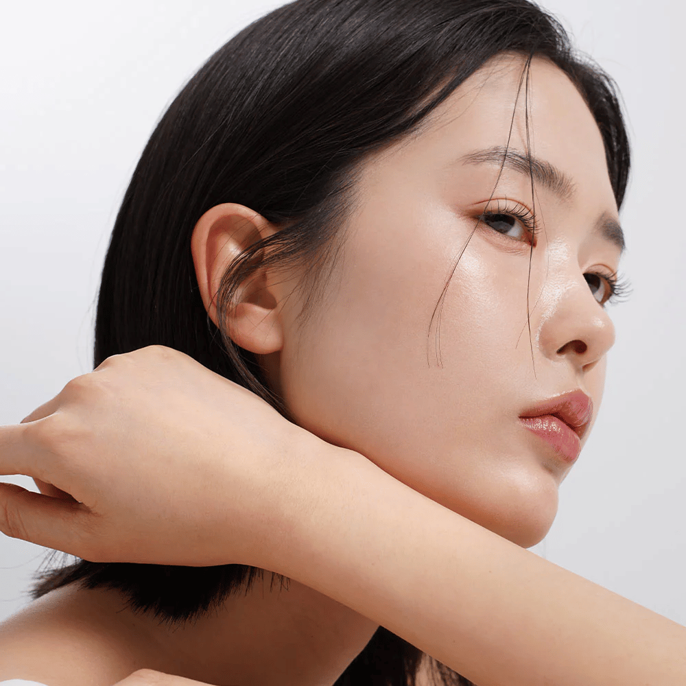 Primer plano de una mujer con piel uniforme, radiante y un brillo natural. Inspiración perfecta para el cuidado de la piel para una tez fresca e hidratada.