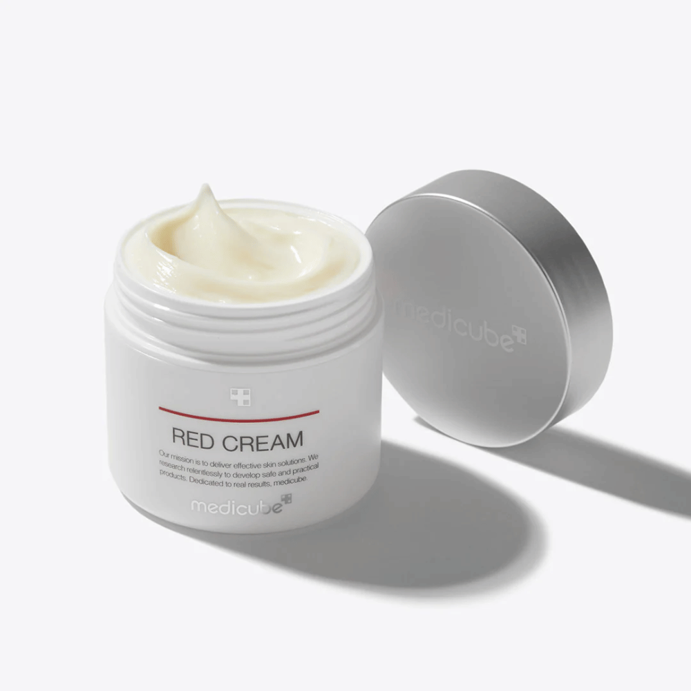 Tarro abierto con medicube Red Cream 50ml – una crema facial de color amarillo claro en un envase blanco con tapa plateada, desarrollada para piel propensa al acné.