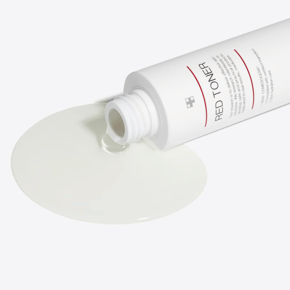 Botella abierta con medicube Red Toner que se vierte sobre una superficie blanca – muestra la consistencia ligera y líquida del producto.