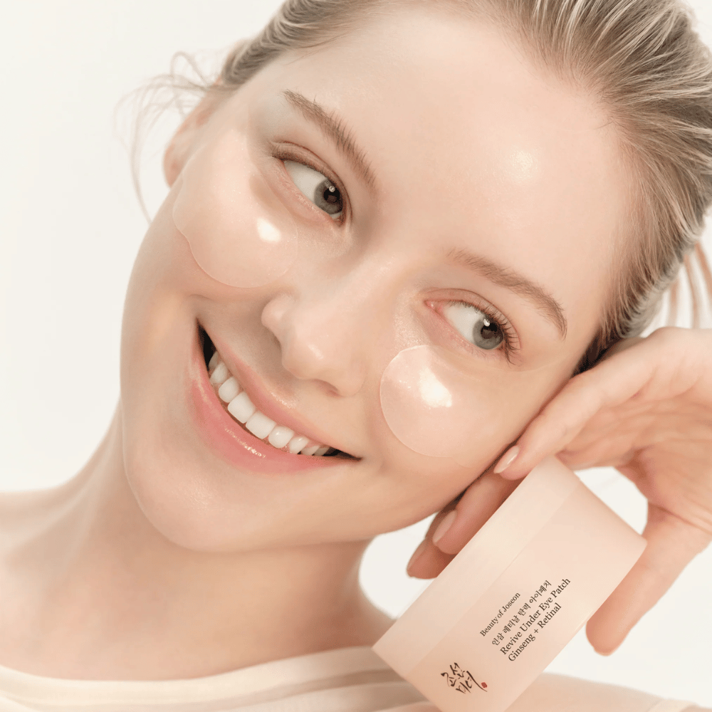 Modelo con Beauty of Joseon parches para ojos y producto en mano, parches para ojos con ginseng y retinal para un área de ojos más despierta y suave.