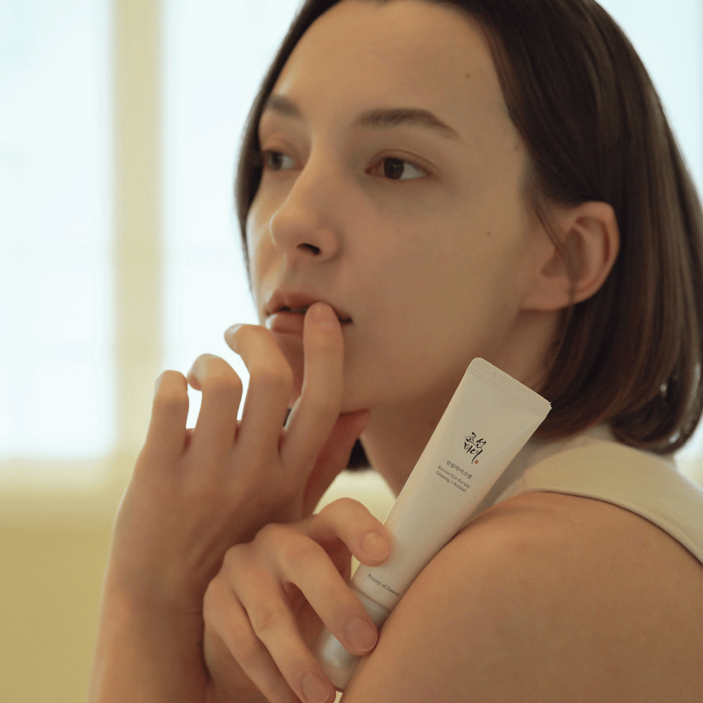 La modelo sostiene Beauty of Joseon Revive Eye Serum y aplica cuidadosamente en la piel para un contorno de ojos hidratado y suave.