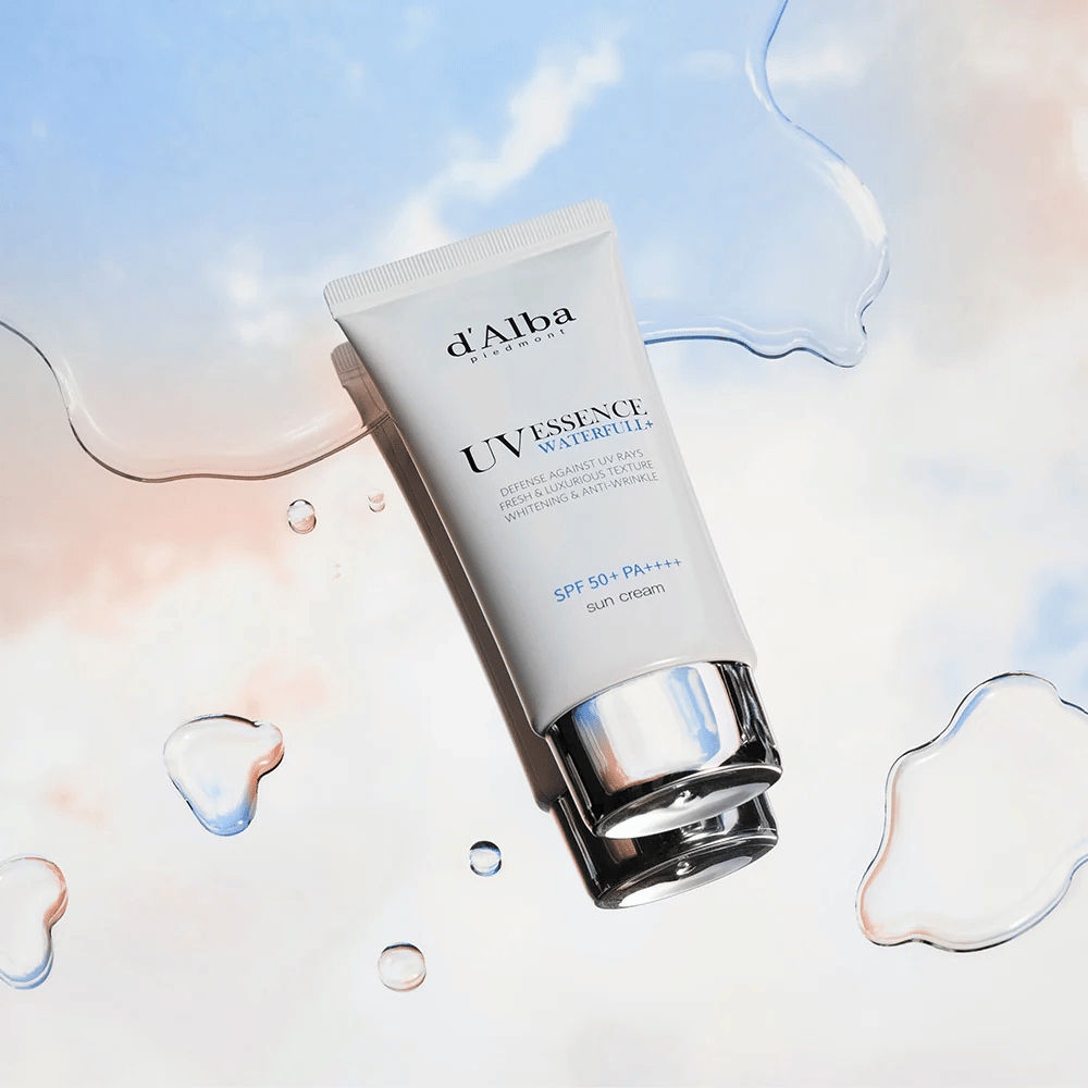 Imagen del producto de d'Alba UV Essence Waterfull+ Sun Cream con SPF 50+ PA++++, colocada contra un fondo con salpicaduras de agua y cielo azul rosado, simboliza protección solar ligera e hidratante.