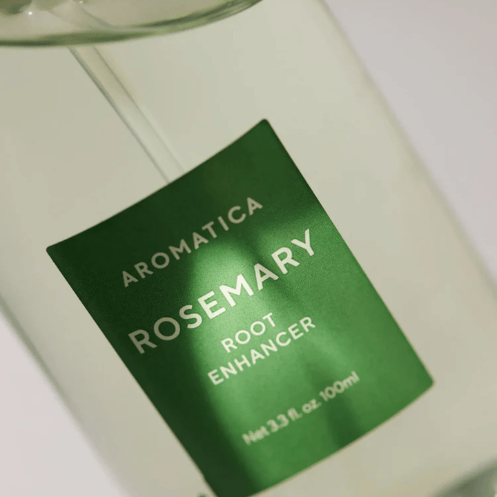 Imagen detallada de la etiqueta de AROMATICA Rosemary Root Enhancer. La etiqueta verde y la botella transparente resaltan el aspecto limpio y minimalista del producto.