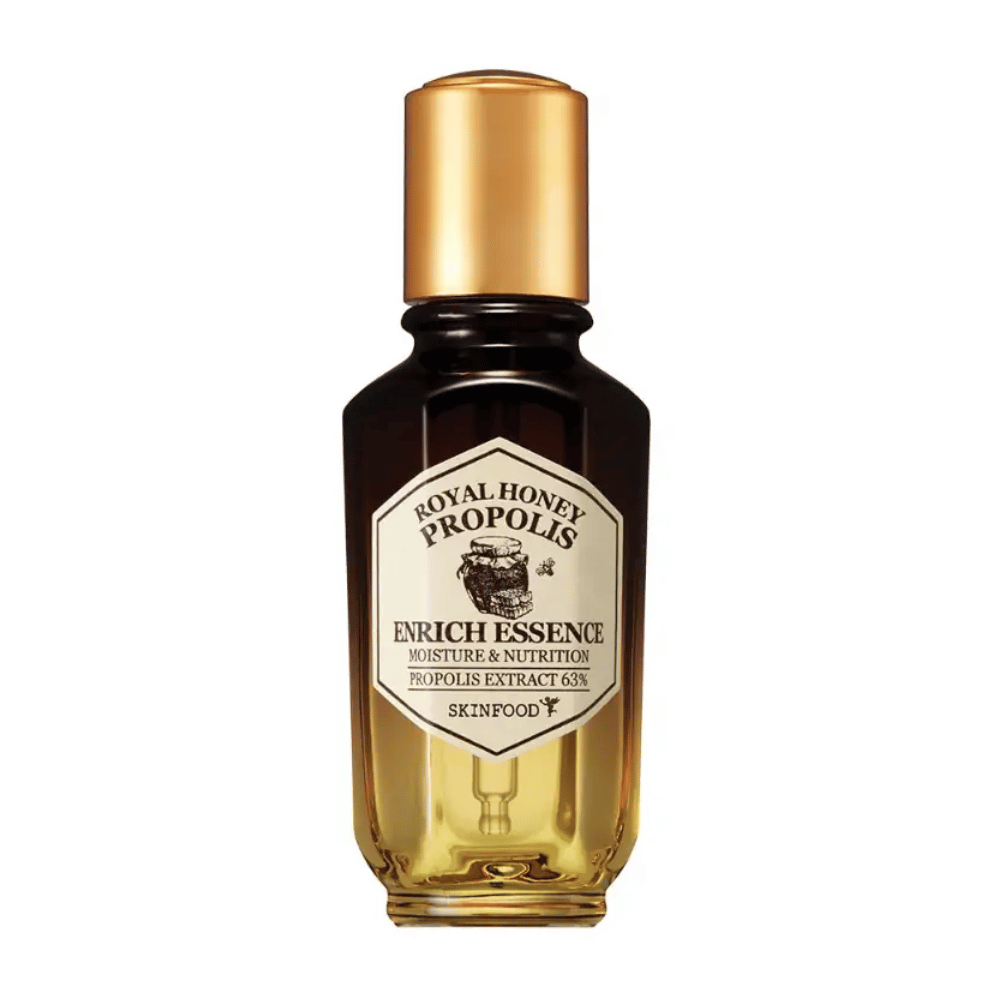 Imagen de una botella de vidrio con líquido oscuro y tapa dorada. En la etiqueta de la botella dice "Royal Honey Propolis Enrich Essence" seguido de "Moisture & Nutrition" y "Propolis Extract 63%". La marca "Skinfood" también se ve al final de la etiqueta.