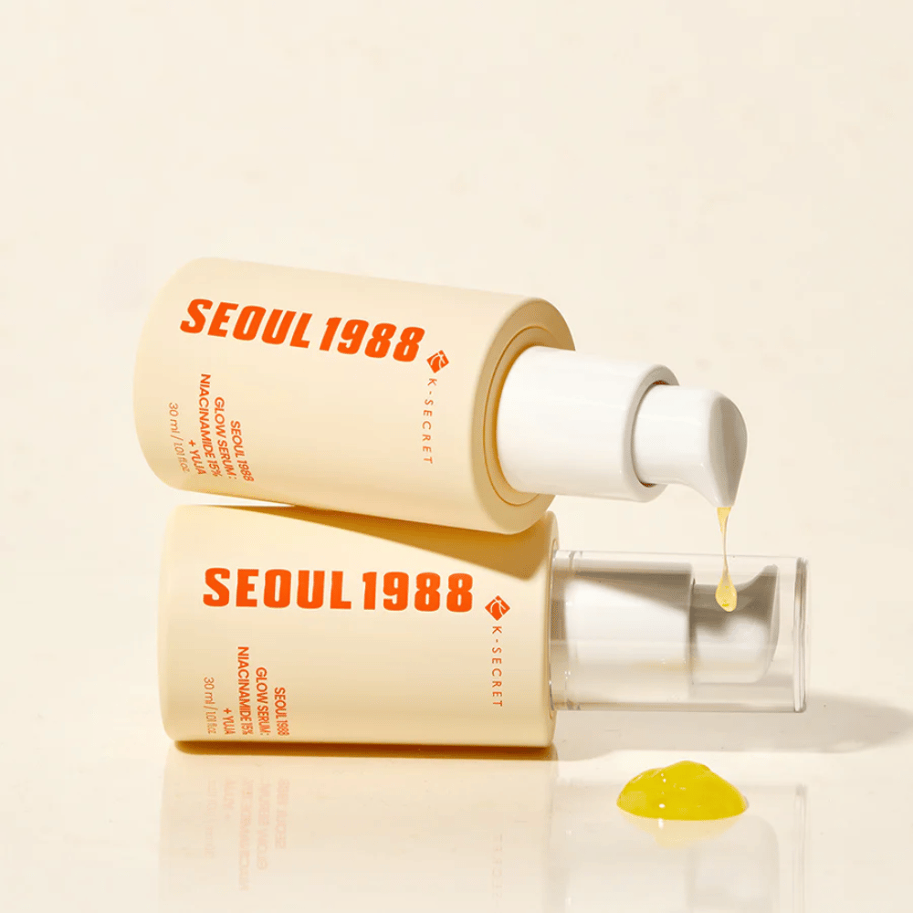 Dos botellas de Seúl 1988 Glow Serum acostadas y de pie, con suero amarillo goteando de la bomba.