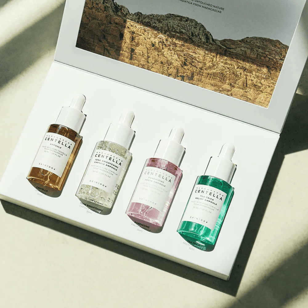 Una caja que contiene Madagascar Centella Ampoule Kit de SKIN1004, que incluye tres tipos diferentes de productos para el cuidado de la piel para la hidratación y humectación.