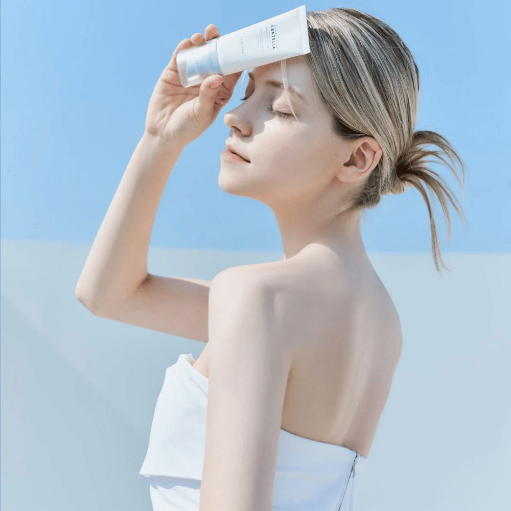 Una mujer aplica SKIN1004 Madagascar Centella Hyalu-Cica Water-Fit Sun Serum 50ml para proteger su rostro de los rayos UV.