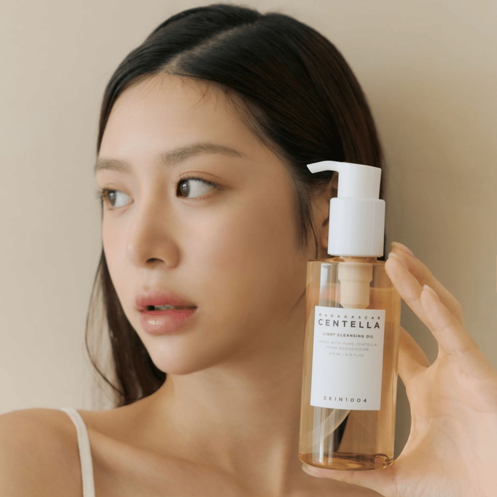 Una mujer sosteniendo una botella SKIN1004 Madagascar Centella Light Cleansing Oil 200 ml de limpiador facial.