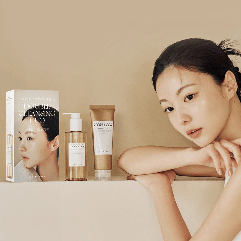 SKIN1004 Madagascar Centella Double Cleansing Duo Set con caja, limpieza a base de aceite, limpieza con espuma y modelo con piel hidratada sobre fondo beige.