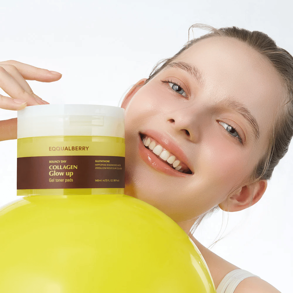 Modelo sonriente sosteniendo Bouncy Day Collagen Glow up Gel Toner Pads, que ayuda a proporcionar un brillo juvenil y firmeza con colágeno de baja masa molecular y glutatión.