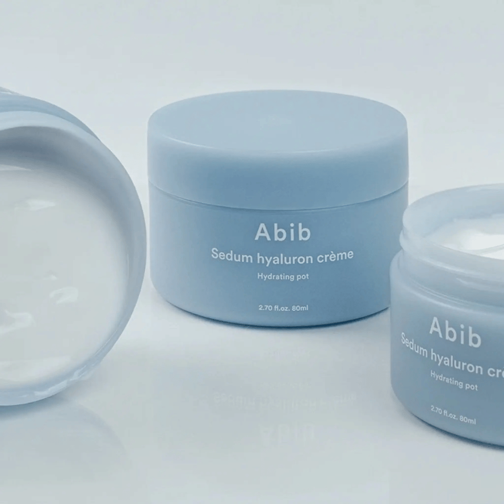 Tres tarros de Abib Sedum Hyaluron Crème Hydrating Pot 80 ml en diseño minimalista azul claro, uno de los cuales muestra la textura blanca cremosa.