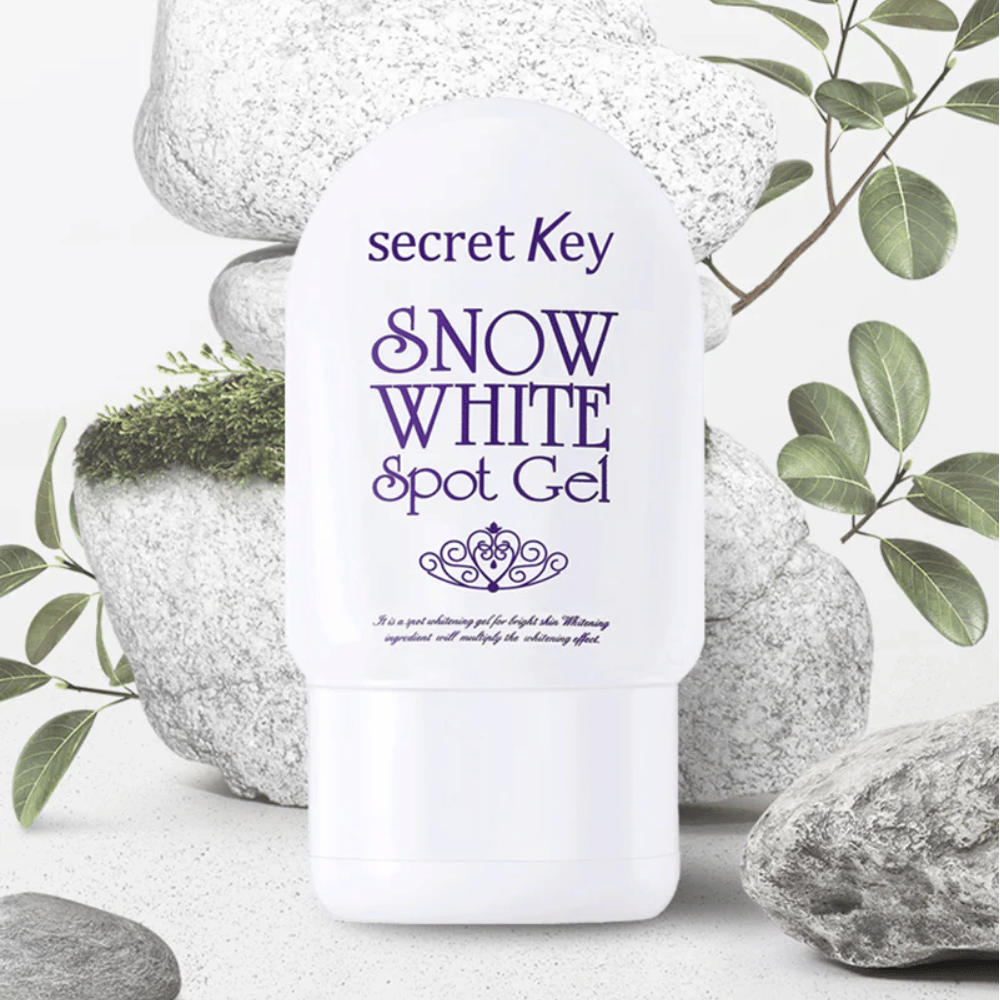 Secret Key Snow White Spot Gel fotografiada contra piedras y hojas verdes.