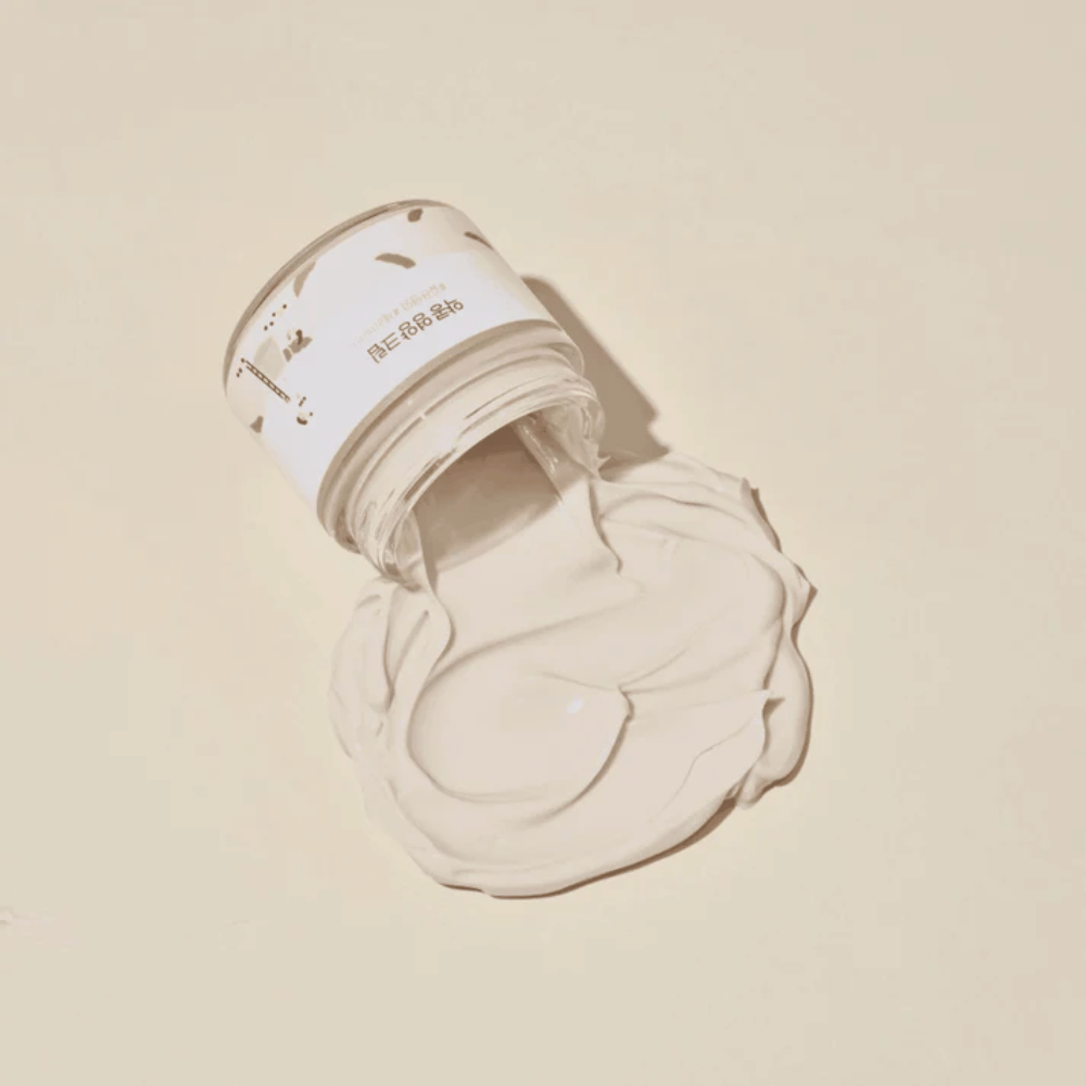 Mixsoon Soybean Nourishing Cream derramada del frasco sobre un fondo beige. La rica consistencia de la crema muestra sus intensas propiedades hidratantes.