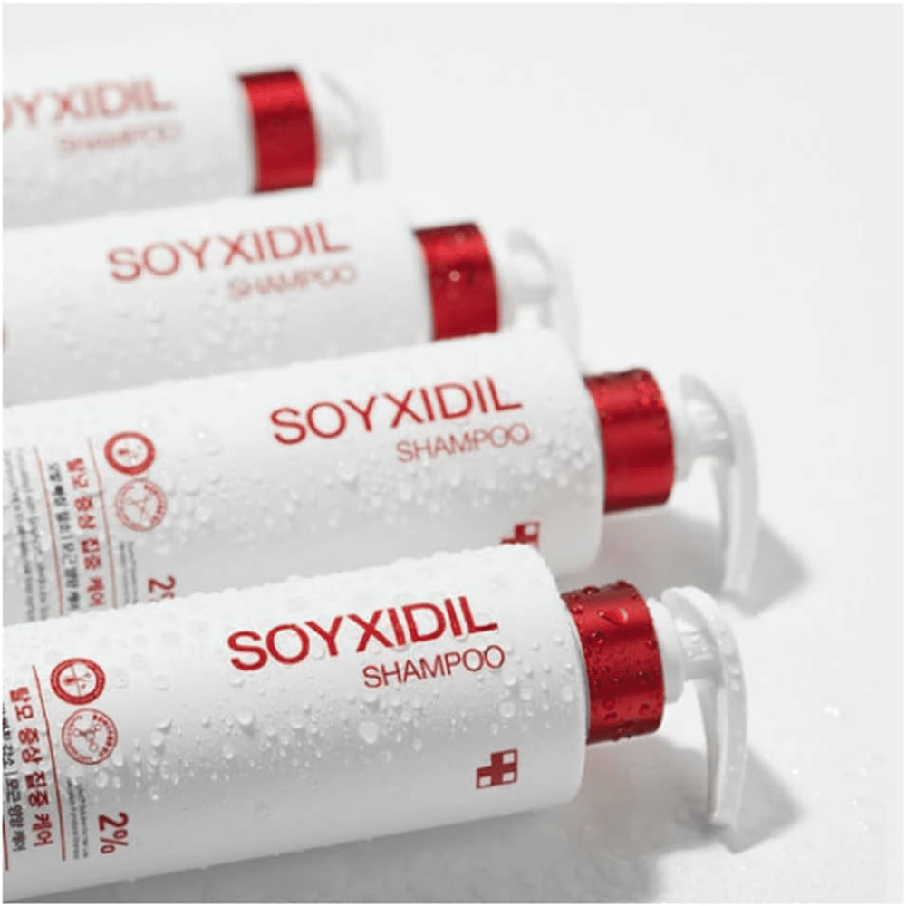 Varias botellas de Medicube Soyxidil Shampoo están alineadas con gotas de agua - muestra la sensación fresca y cuidada del producto.