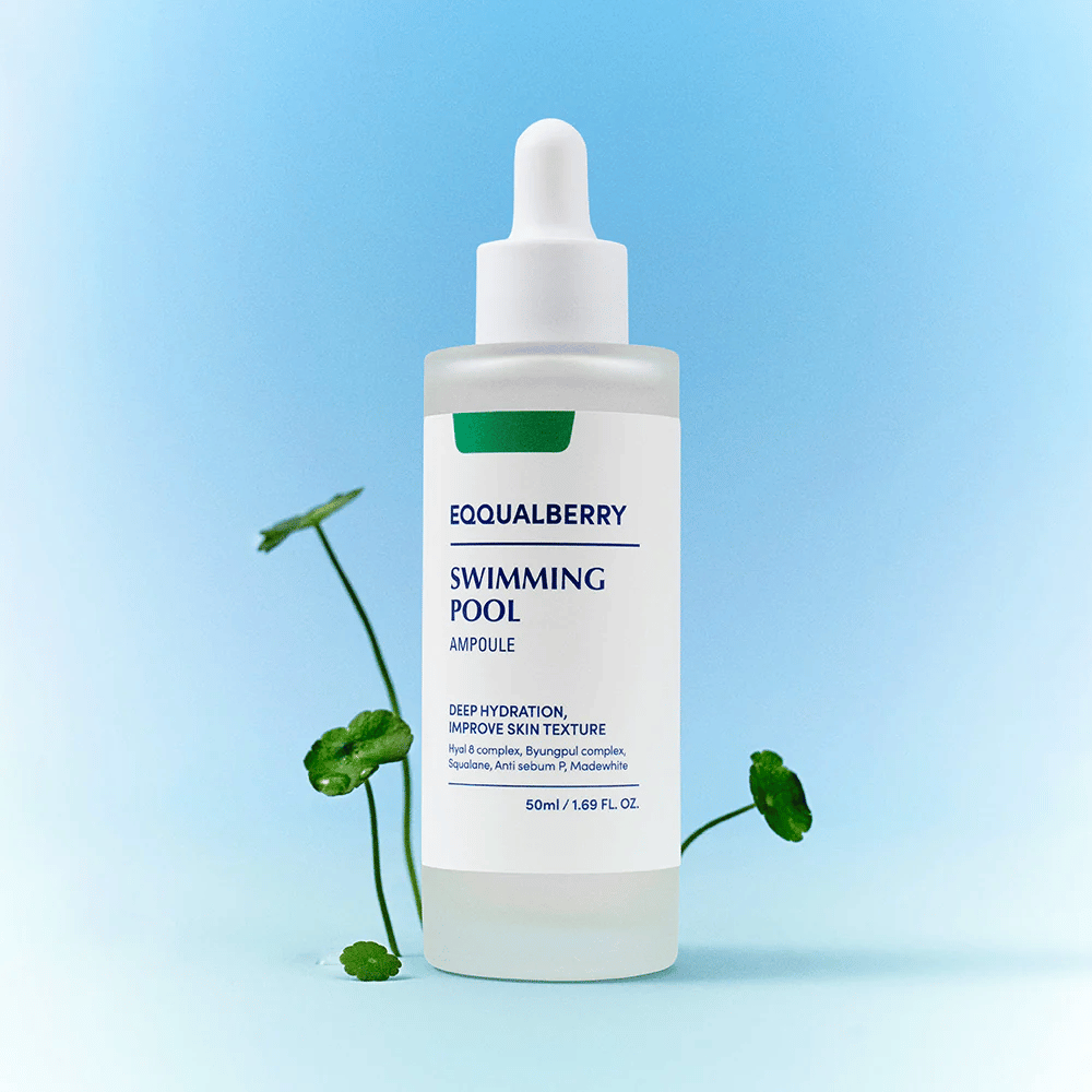 Botella con Eqqualberry Swimming Pool Ampoule, un producto para el cuidado de la piel para hidratación profunda y mejora de la estructura de la piel, colocada sobre un fondo azul claro con algunas plantas verdes en primer plano.