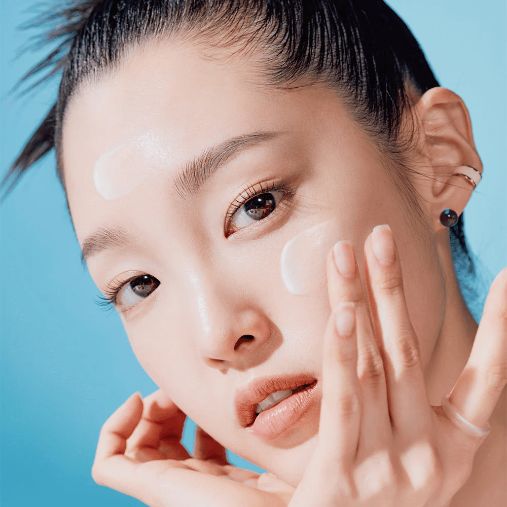 Una mujer posa con las manos en la cara en una TOCOBO Bio Watery Sun Cream SPF50+ PA++++ campaña de cuidado natural de la piel de 50ml.