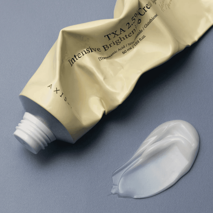 Imagen del producto con el tubo y una pequeña cantidad de crema al lado para mostrar la textura suave y cremosa y la fórmula hidratante. El enfoque está en el brillo y la aplicación uniforme.