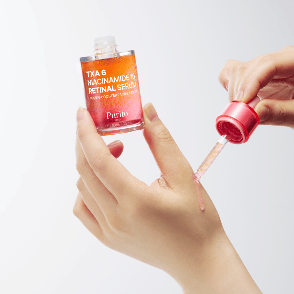 Mano aplicando Purito TXA 6 Niacinamide 10 Retinal Serum. Fórmula ligera con ingredientes activos para brillo, elasticidad y piel más clara.
