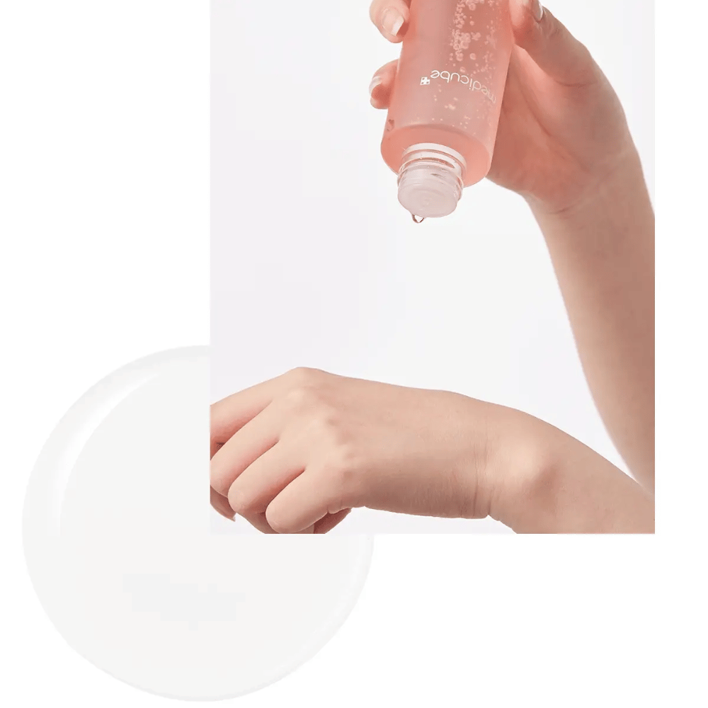 Mano vertiendo Medicube Triple Collagen Toner 4.0 de una botella rosa sobre la piel, mostrando la consistencia hidratante.