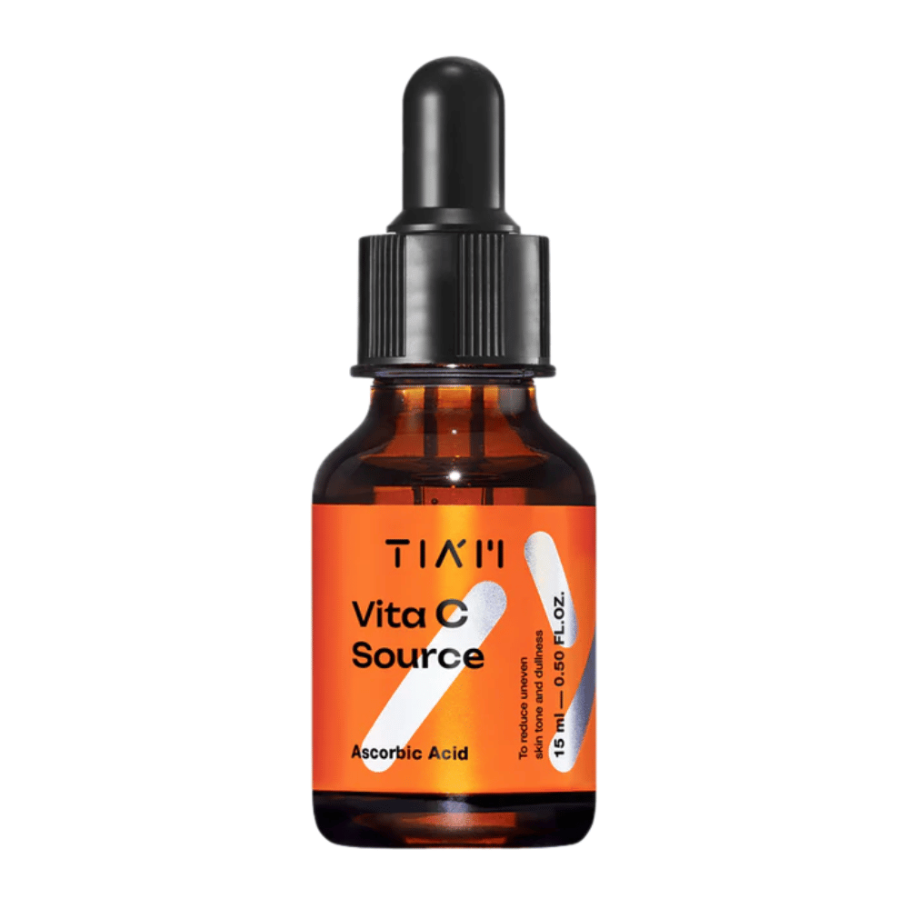 TIA'M Vita C Source, un suero con ácido ascórbico en botella de vidrio marrón con pipeta negra y etiqueta naranja – eficaz para iluminar la piel y reducir el tono desigual de la piel.
