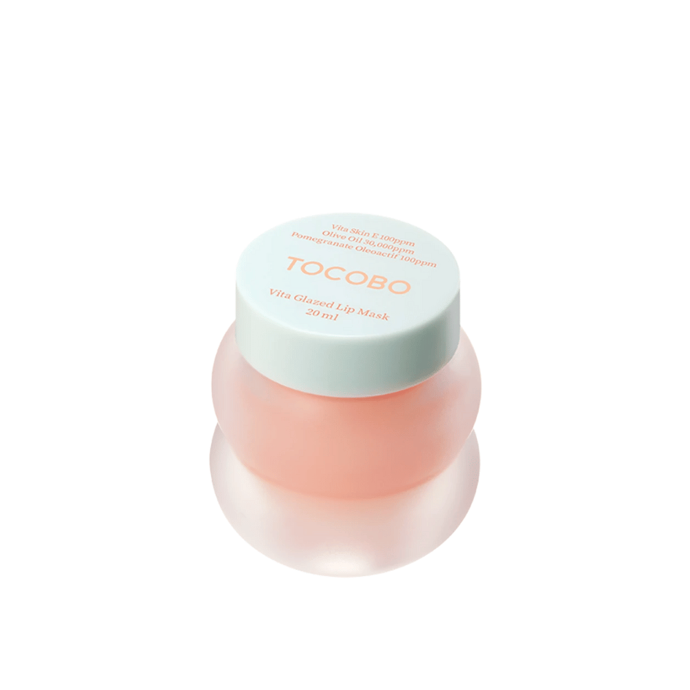 Un frasco de "Vita Glazed Lip Mask" de Tocobo se muestra. El frasco es redondo y transparente con una tapa turquesa clara. La mascarilla dentro es de un rosa suave y está diseñada para hidratar y cuidar los labios. El producto tiene un volumen de 20 ml.