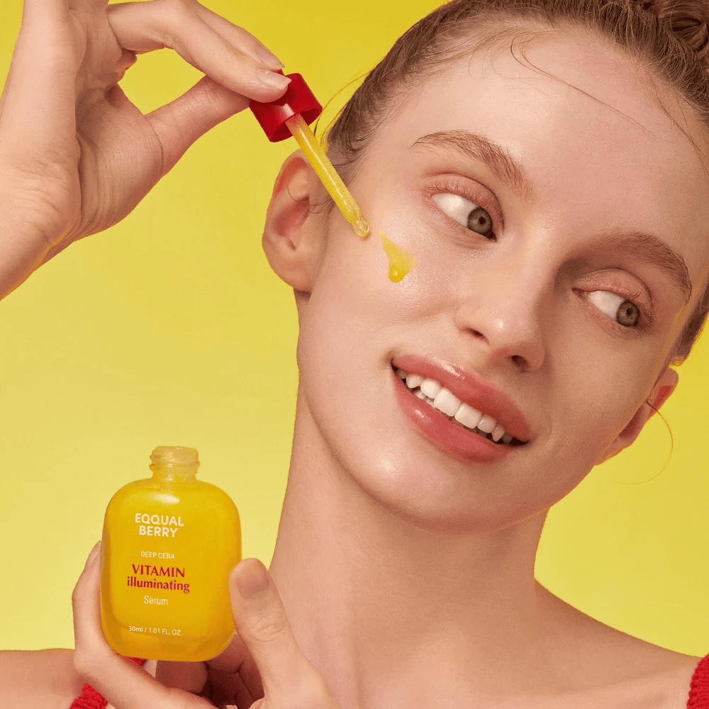 Mujer sonriente aplica Equal Berry Vitamin Illuminating Serum con una pipeta. Piel fresca y radiante contra un fondo amarillo vibrante que coincide con el color del suero.