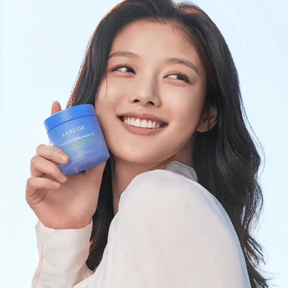 Mujer sonriente sostiene un tarro azul de LANEIGE Water Sleeping Mask frente a un fondo azul claro.