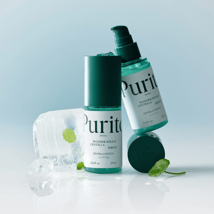 Två flaskor av Purito Wonder Releaf Centella Serum, en stående och en liggande, omgivna av isbitar med centellablad inuti samt ett löst blad på en ljusblå yta.