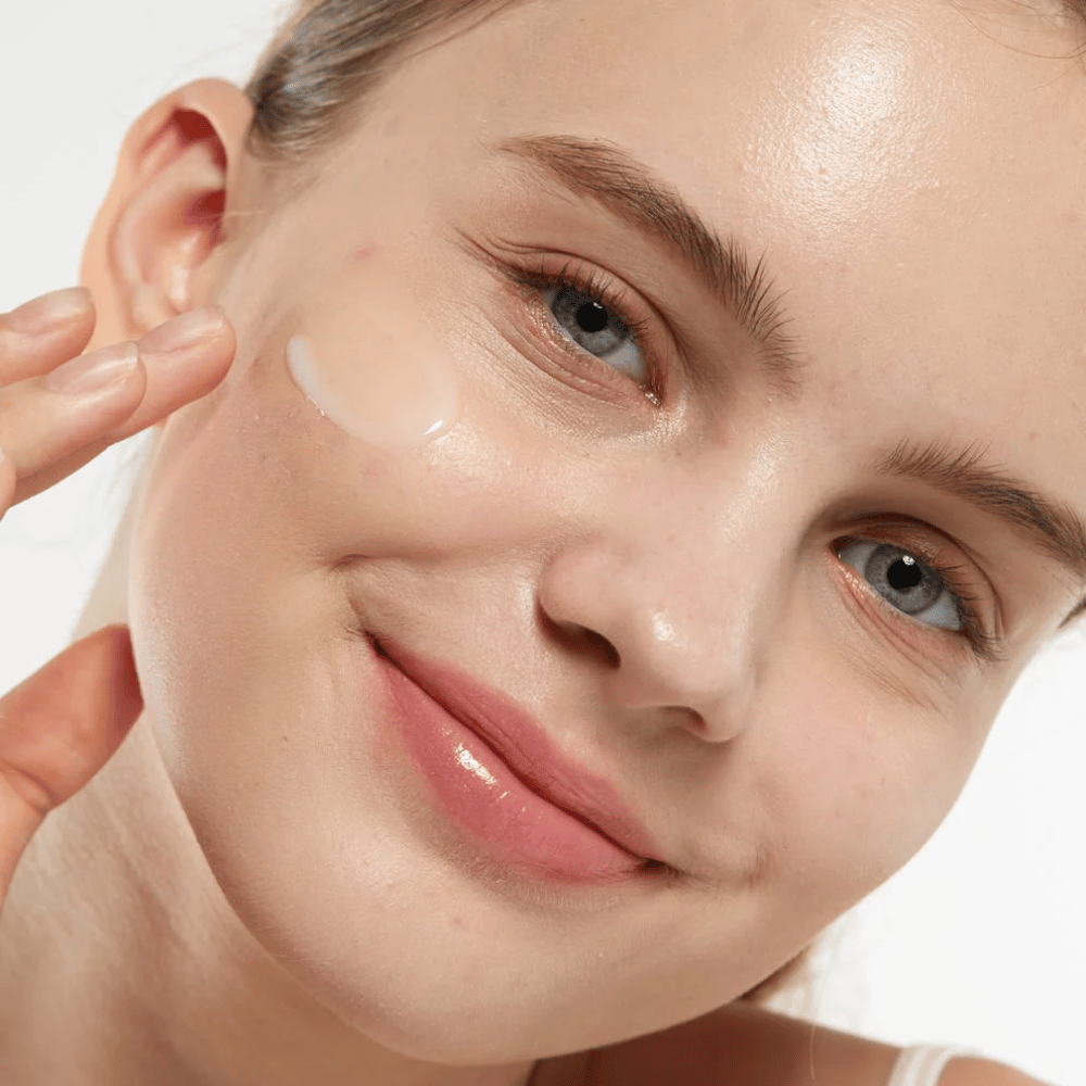Modelo aplicando Medicube Zero Pore Serum 2.0 en la mejilla, un suero refinador de poros que proporciona una textura de piel más uniforme, hidratación y un brillo natural.