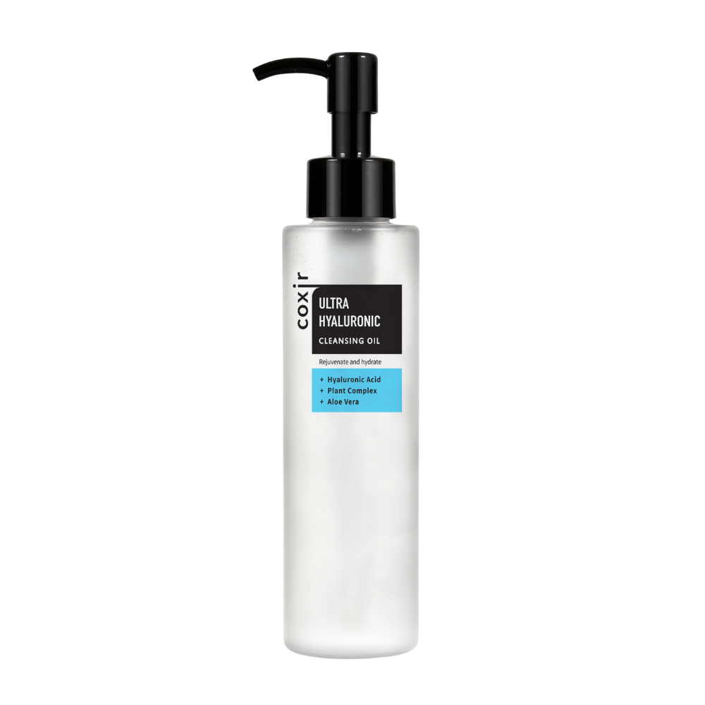 Una botella de bomba blanca con el texto "coxir ULTRA HYALURONIC CLEANSING OIL", que contiene ácido hialurónico, complejo vegetal y aloe vera para hidratación y purificación.