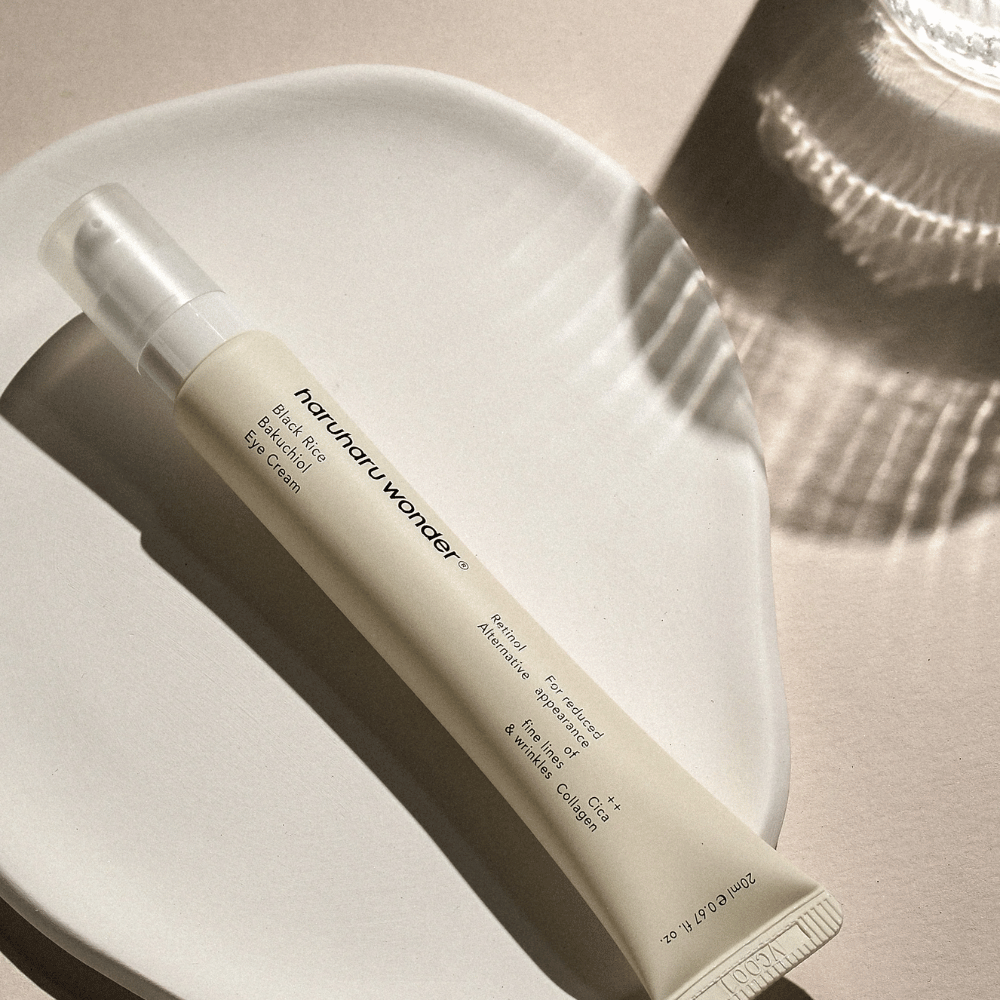 HaruHaru Wonder Black Rice Bakuchiol Eye Cream 20 ml – crema para ojos con arroz negro, bakuchiol y colágeno que reduce líneas finas y arrugas, colocada en un plato de cerámica en luz suave.