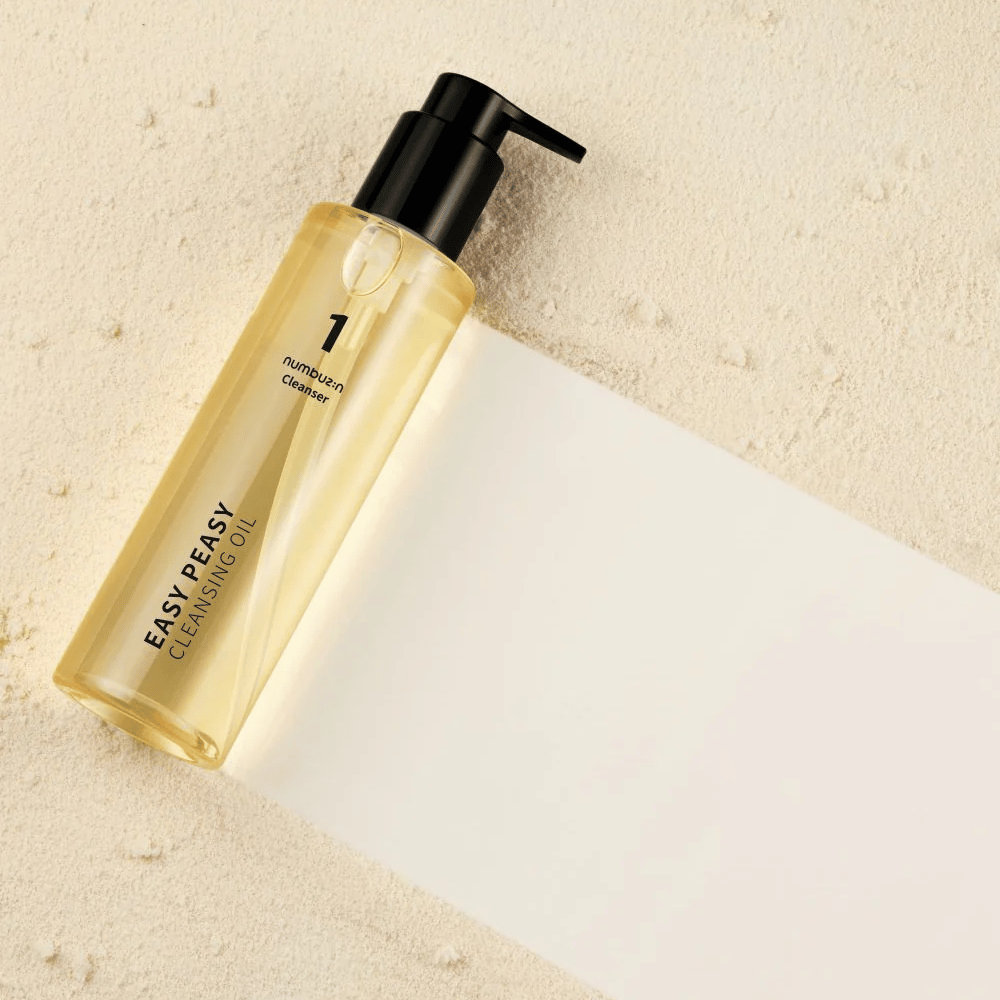 Numbuzin No.1 Easy Peasy Cleansing Oil tumbado sobre una superficie color arena con sombra.