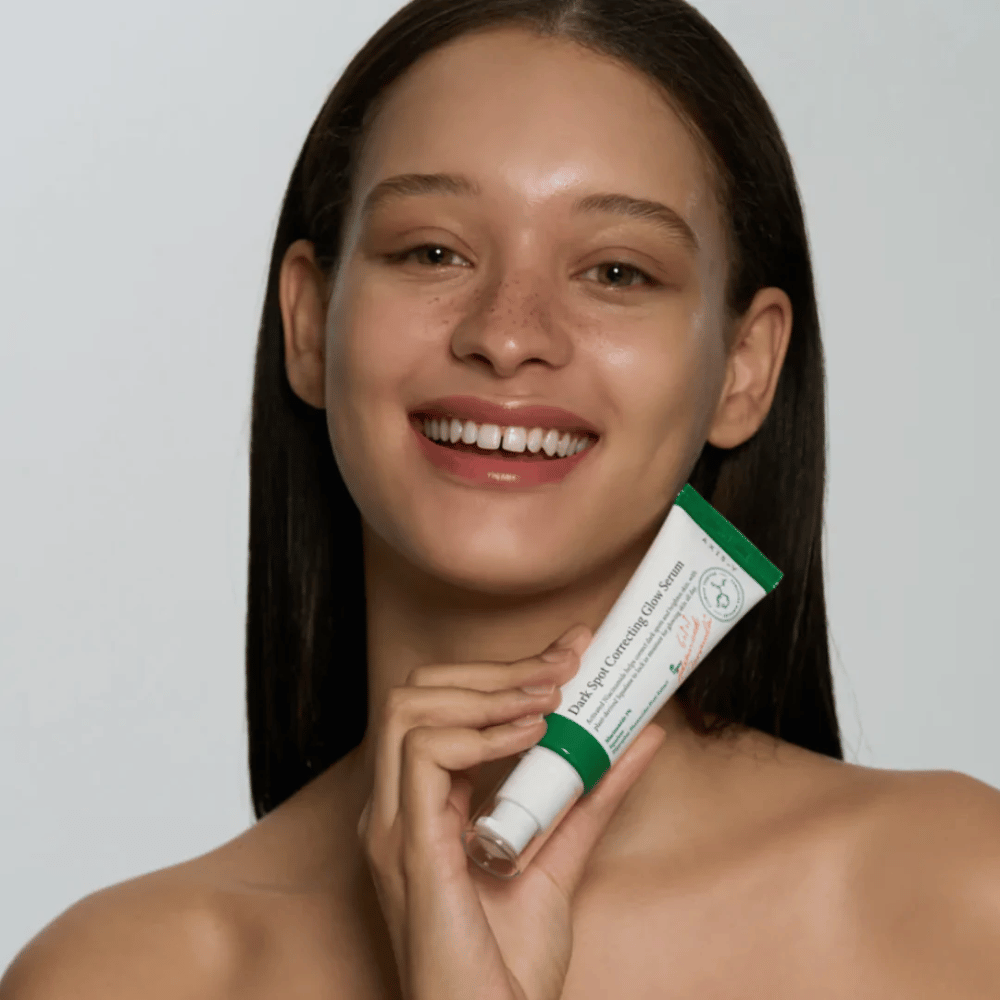 Una joven sostiene un tubo con AXIS - Y Dark Spot Correcting Glow Serum 50ml.