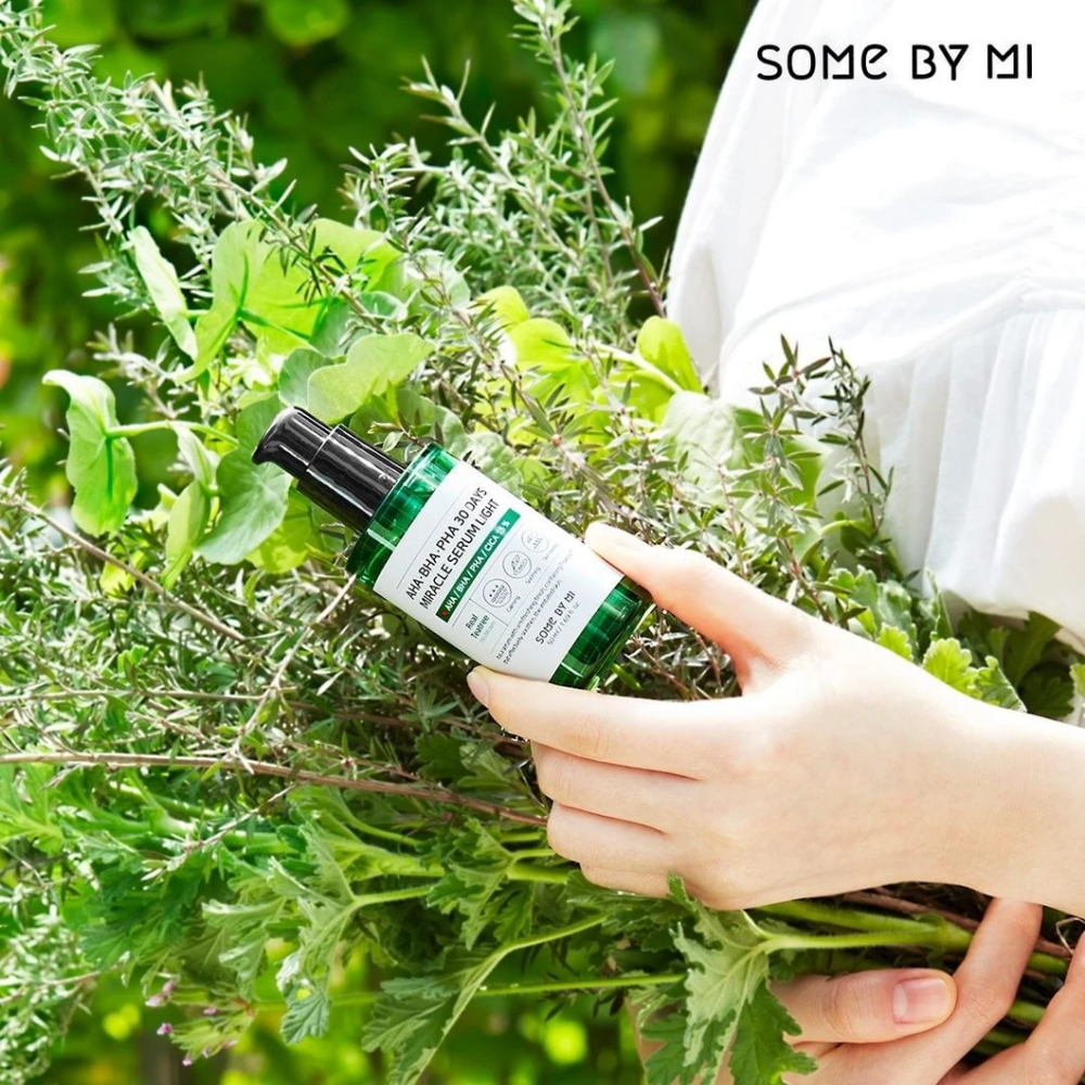 Una mujer que sostiene un manojo de hierbas en las manos para combatir manchas pigmentarias y acné con la ayuda de AHA, BHA, PHA 30 Days Miracle Serum Light 50ml de SOME BY MI.