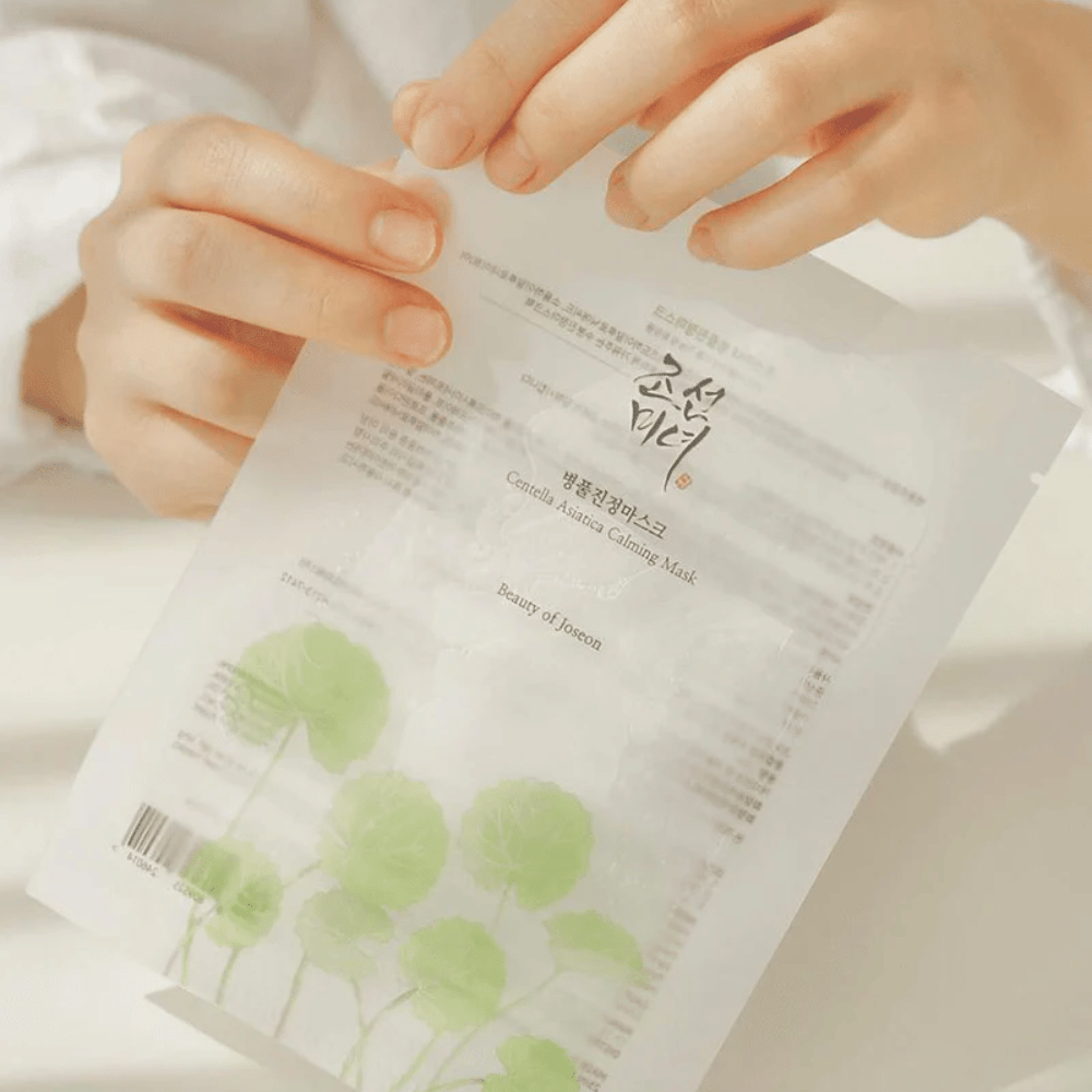 Una persona que sostiene una hoja de papel con un Beauty of Joseon Centella Asiatica Calming Mask 1 unidad en él.