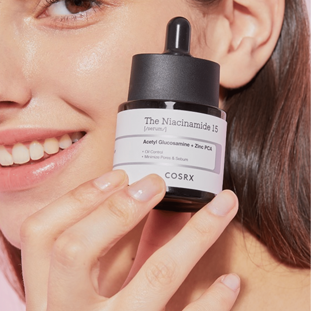 Una mujer sostiene una botella de COSRX Niacinamida 15 Serum 20ml para niacinamida y la producción de sebo.