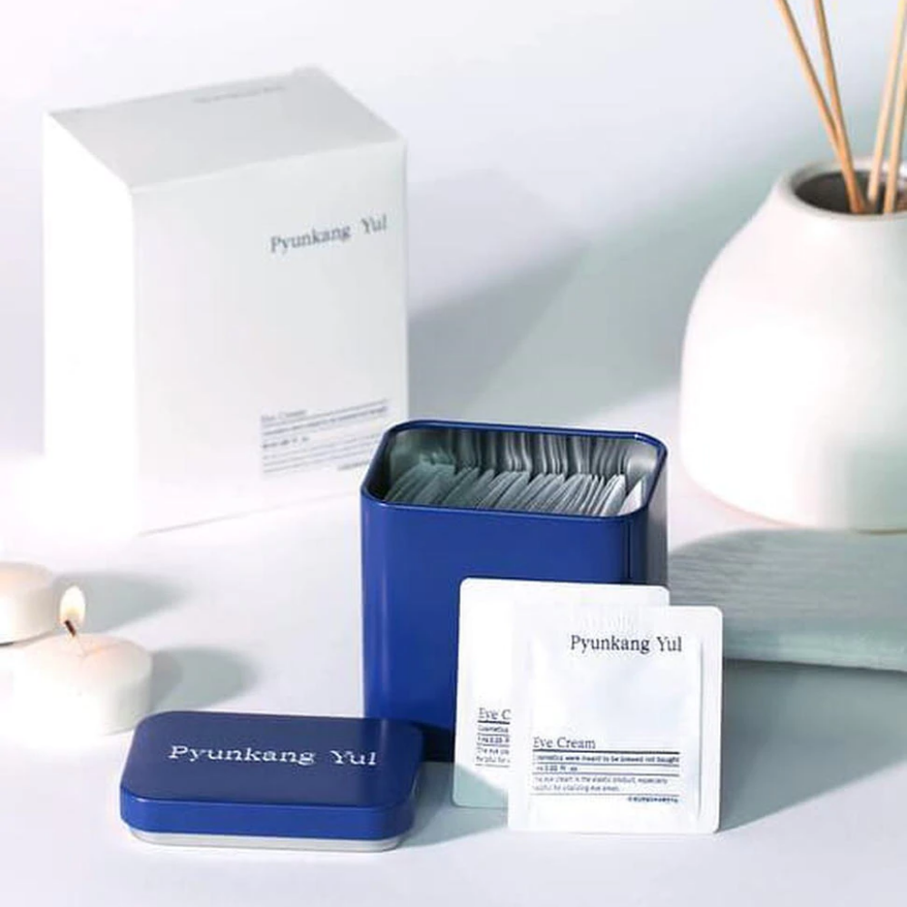 Una caja blanca con tapa azul y Pyunkang Yul Eye Cream 1ml x 50st al lado.