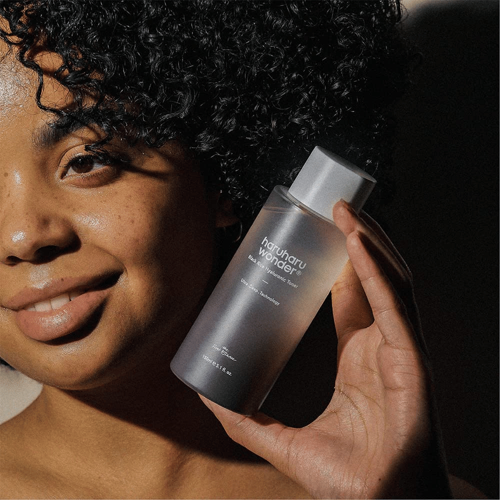 Una mujer sosteniendo una botella de Haruharu Wonder Black Rice Hyaluronic Toner Original 150ml.