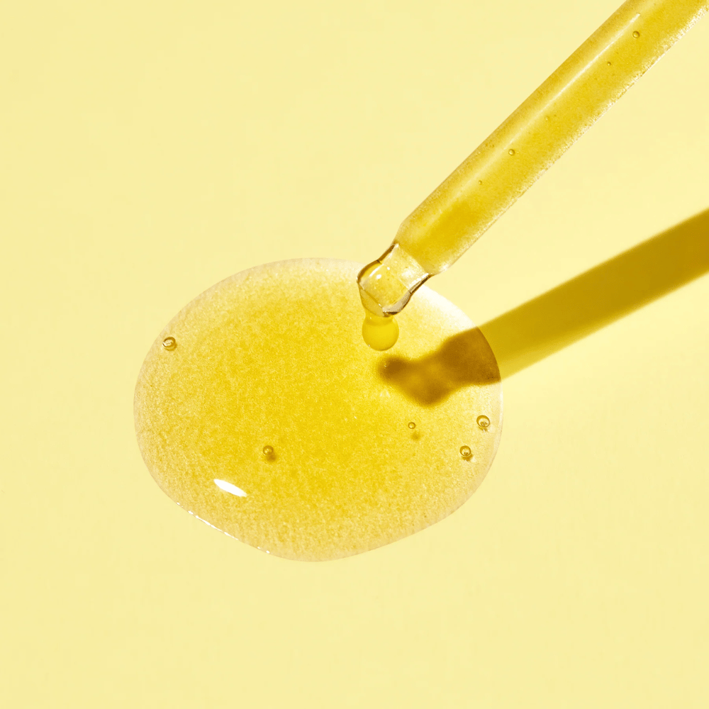 Una gota de líquido sobre un fondo amarillo, con MISSHAs Vita C Plus Spot Correcting & Firming Ampoule.