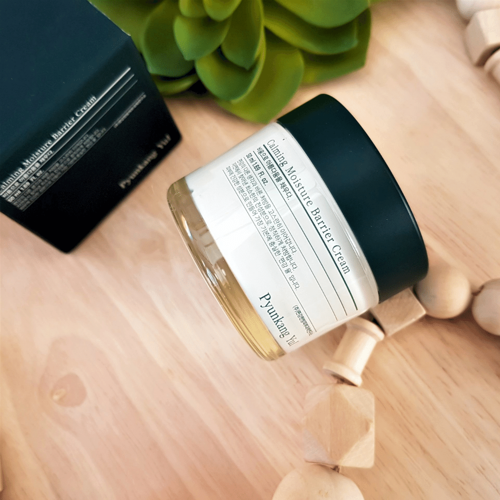 Un frasco Pyunkang Yul Calming Moisture Barrier Cream 50ml que está sobre una mesa de madera.